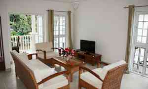 En lys stue med sittegruppe for fire personer, et sofabord og en TV. (AI-generert tekst)