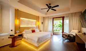 Et moderne soverom med en stor seng, sitteplasser og en åpen balkong med utsikt over grøntområder. (AI-generert tekst)