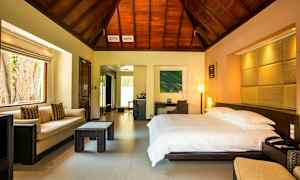 Et hotellrom med en stor seng, sofa og bord, trepanel i taket. (AI-generert tekst)