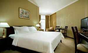 Et hotellrom med en stor oppredd seng, lamper, spisebord og en TV. (AI-generert tekst)