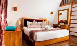 Et stilrent soverom med en dobbeltseng, tredetaljer og dekorerte puter. (AI-generert tekst)