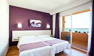 Rom med dobbeltseng, lilla vegg og balkong med sjøutsikt. (AI-generert tekst)