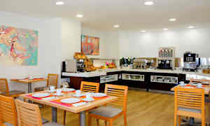 Spiseplass med dekket bord og buffet med kaffemaskin og frokostalternativer. (AI-generert tekst)