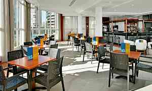 Restaurant med bord og stoler på et lyst gulv. (AI-generert tekst)