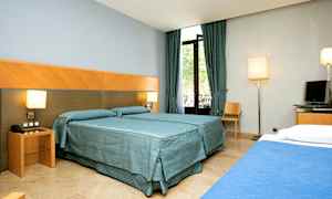 Hotellrom med to senger, gardiner og vindu. (AI-generert tekst)