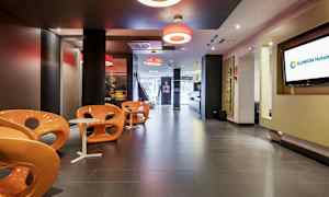 En moderne hotellobby med oransje stoler og små hvite bord. (AI-generert tekst)