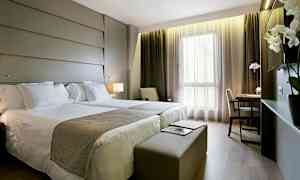 Et hotellrom med to senger, skrivebord og store vinduer. (AI-generert tekst)