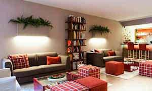 En moderne stue med sofaer, en bokhylle og en bardisk i bakgrunnen. (AI-generert tekst)