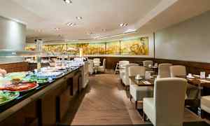 Bildet viser en bufférestaurant med moderne møbler og et utvalg av mat lagt opp på en buffédisk. (AI-generert tekst)