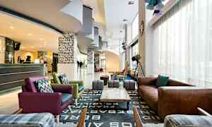 En hotellobby med sittegrupper, en resepsjon og dekorasjoner. (AI-generert tekst)