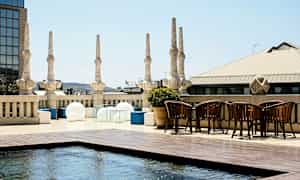 En takterrasse med søyler, moderne møbler og et grunt vannbasseng. (AI-generert tekst)