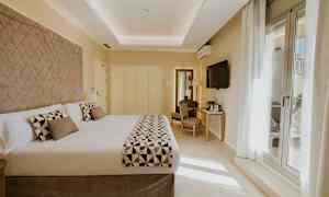 Et hotellrom med en stor dobbeltseng, TV på veggen og et skrivebord med stol. (AI-generert tekst)