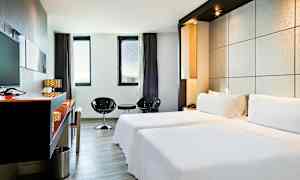 Et elegant hotellrom med to enkeltsenger, minimalistisk innredning og store vinduer som slipper inn naturlig lys. (AI-generert tekst)