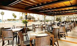 Restaurant med sitteplasser utendørs ved bassengområdet. (AI-generert tekst)