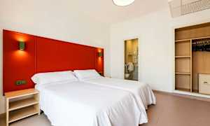 Hotellrom med to enkeltsenger, et skap og et åpent bad. (AI-generert tekst)