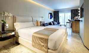 Et moderne hotellrom med en stor seng, sofagruppe og en minibar foran et stort vindu. (AI-generert tekst)