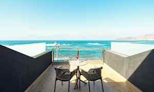 En terrasse med to stoler og et bord med utsikt over havet. (AI-generert tekst)