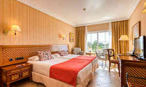 Bilde av et hotellrom med to senger, stol og bord, samt en TV. (AI-generert tekst)