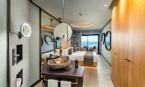 Interiør av et elegant hotellrom med seng, bad og utsikt mot havet. (AI-generert tekst)