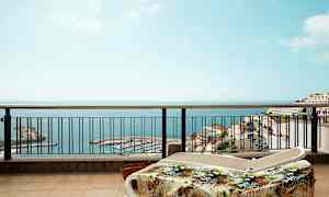 Solstoler på en terrasse med utsikt over havet og en havn. (AI-generert tekst)