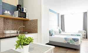 Interiør av et hotellrom med et kjøkken og to enkeltsenger. (AI-generert tekst)