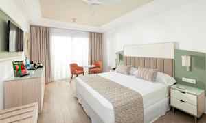 Hotellrom med dobbeltseng, TV, sittegruppe og garderobe. (AI-generert tekst)