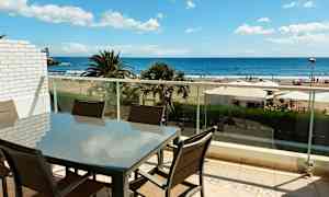 En møbelgruppe på en balkong med utsikt over stranden og havet. (AI-generert tekst)