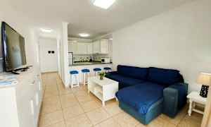 En stue med mørkeblå sofa og åpen kjøkkenløsning. (AI-generert tekst)