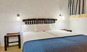 Et soverom med en dobbeltseng, blå-rutete sengegavl og hvitt sengetøy. (AI-generert tekst)