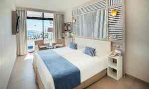 Dobbeltrom med havutsikt, møbler i lyse farger. (AI-generert tekst)