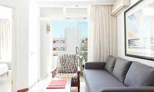 Stue med grå sofa, lenestol og et kunstverk på veggen, med utsikt mot balkongen. (AI-generert tekst)