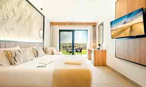 Moderne hotellrom med stor seng, skrivebord og utsikt til en terrasse. (AI-generert tekst)