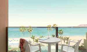 Balkong med utsikt over strand og hav, bord og stoler synlige. (AI-generert tekst)