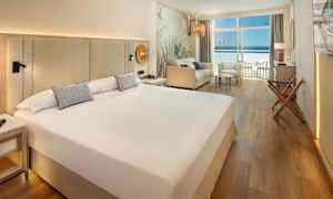 Hotellrom med stor seng, sittegruppe og balkong med havutsikt. (AI-generert tekst)