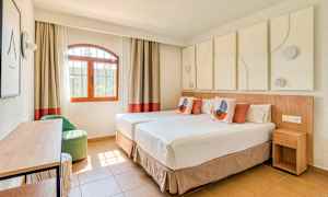 Et lyst og moderne innredet hotellrom med to enkeltsenger, en vindusutsikt og dekorative elementer. (AI-generert tekst)