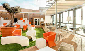 Område utendørs med sitteplasser, bord og et tre plantet i en stor potte. (AI-generert tekst)