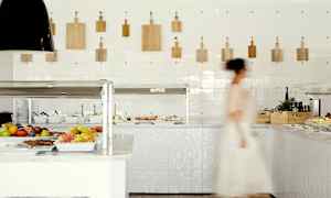 Bilde av et buffetområde med frukt og salat, en person passerer. (AI-generert tekst)