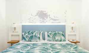 Seng med grønn- og hvitmønstret dyne og puter, med blå sengegavl og hvite vegger. (AI-generert tekst)