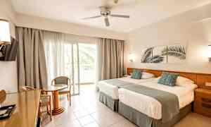 Hotellrom med to senger, sittegruppe og balkong. (AI-generert tekst)