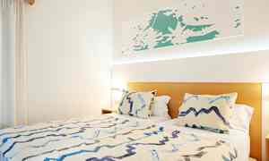 Seng med to puter og et teppe i et lyst rom. (AI-generert tekst)