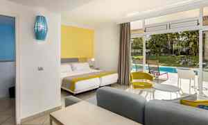 Et hotellrom med fargerik innredning og utsikt mot en hage med basseng. (AI-generert tekst)