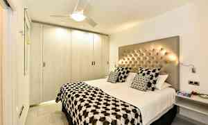 Et moderne soverom med en dobbeltseng, knappet hodegjerde og mønstret sengetøy. (AI-generert tekst)