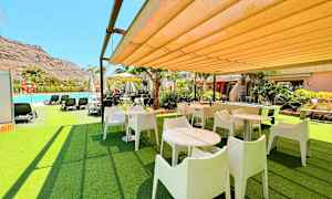 Utendørsområde med bord, stoler og nærliggende basseng. (AI-generert tekst)