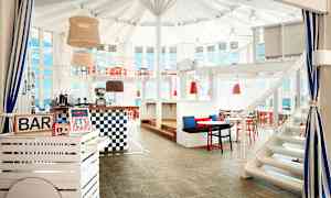 En innendørsbar med hvite og røde møbler samt store vinduer. (AI-generert tekst)