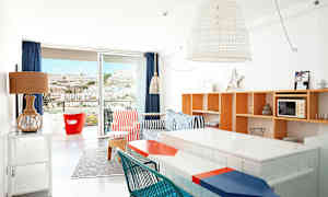 Lyst innredet leilighet med fargerike møbler og utsikt mot et fjell gjennom balkongdøren. (AI-generert tekst)