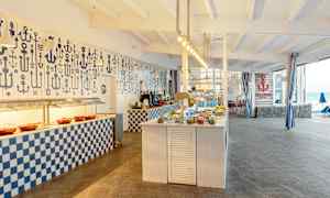 Bilde av en bufférestaurant med maritimt tema, med oppdekkede bord og dekorasjoner. (AI-generert tekst)