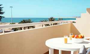 Balkong med havutsikt, et bord med fruktskål og glass med juice. (AI-generert tekst)