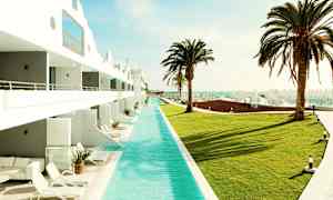 Et basseng ved et hotell med gressplen og palmer. (AI-generert tekst)