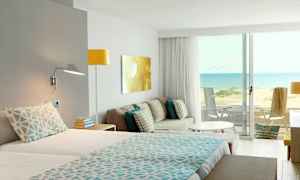 Hotellrom med utsikt over en sandstrand og havet. (AI-generert tekst)