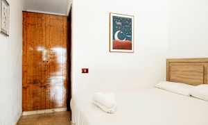 Et lite rom med en tre-seng og hvitt sengetøy. På veggen henger et maleri med en måneillustrasjon. (AI-generert tekst)